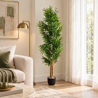 180 cm artificial bamboo tree in a black pot beside a beige sofa, gold floor lamp and sunlit window.