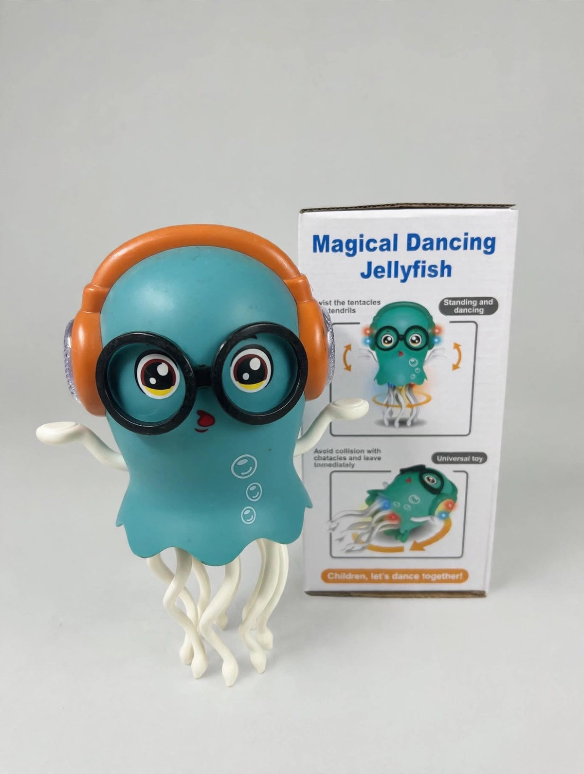 Blue dancing jellyfish toy with orange headphones and black glasses beside its retail packaging.