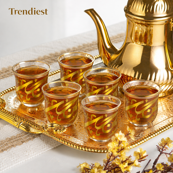 Gold calligraphy glass coffee cups beside a gold coffee pot on a serving tray
