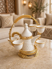 Trendiest white ceramic Arabic coffee dallah and cup set with gold accents in an ornate gold metal serving stand