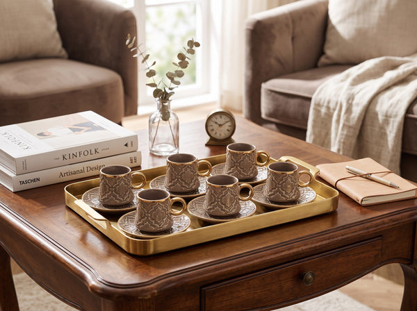 Trendiest decorative ceramic coffee cup and saucer set with gold rims and embossed patterns on a gold serving tray.