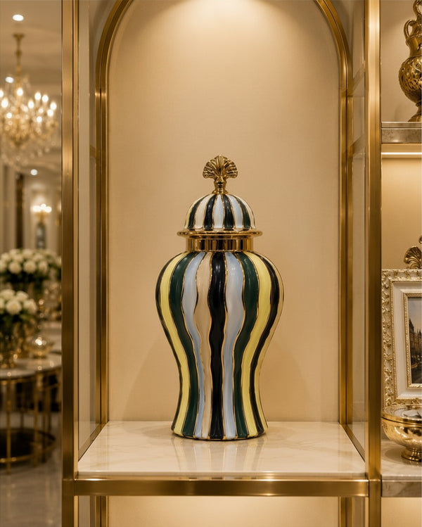 Trendiest ceramic urn vase with gold, emerald green, navy, and ivory stripes on a luxury display shelf.