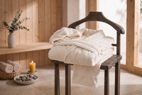 Trendiest spa bathrobe set in cream cotton and nanofiber with matching shower cap and face towel on a wooden chair
