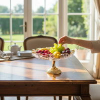 Trendiest glass serving bowl with a gold pedestal base filled with fresh fruit on a wooden dining table