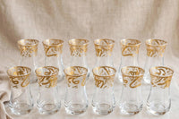 Trendiest set of 6 clear glass tea cups with ornate gold Arabic calligraphy detailing in a tulip-shaped silhouette.