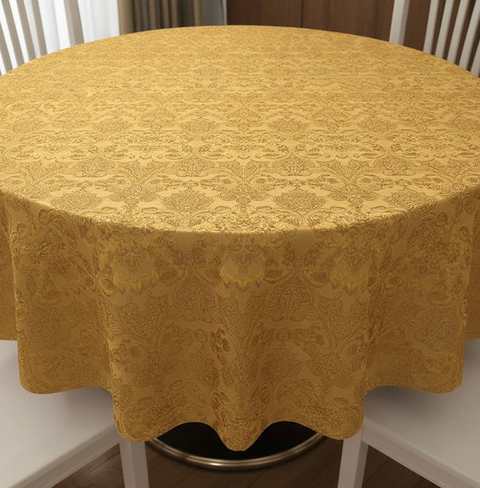 Trendiest round gold tablecloth with an intricate damask textured pattern draped over a dining table