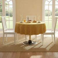 Trendiest gold textured tablecloth on a round dining table with white chairs in a bright, sunlit dining room.