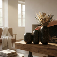 Trendiest set of three matte black ceramic vases with white marble veining, styled with dried florals on a wood table.