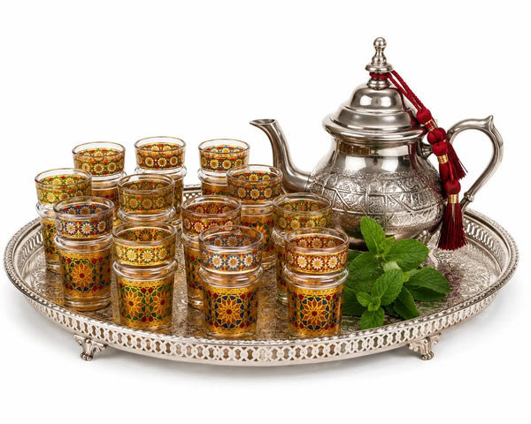 Trendiest set of 12 Moroccan tea glasses with gold geometric patterns and matching silver teapot on a serving tray.