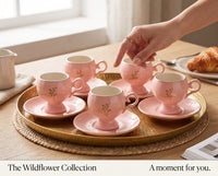 Trendiest pink ceramic cup set with gold wildflower accents on a gold serving tray, hand reaching for a cup