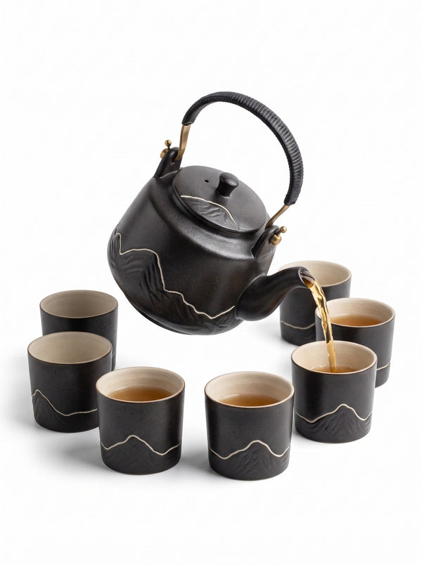 Trendiest high-fired porcelain tea set with a black textured finish and mountain motif, pouring tea into matching cups