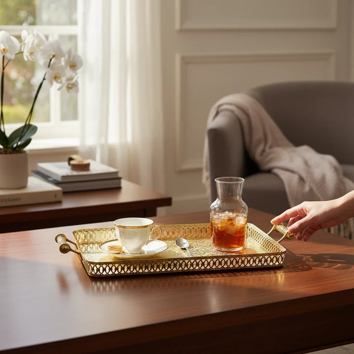 Trendiest rectangular gold serving tray with ornate lattice border and handles on a wooden table with tea and drink