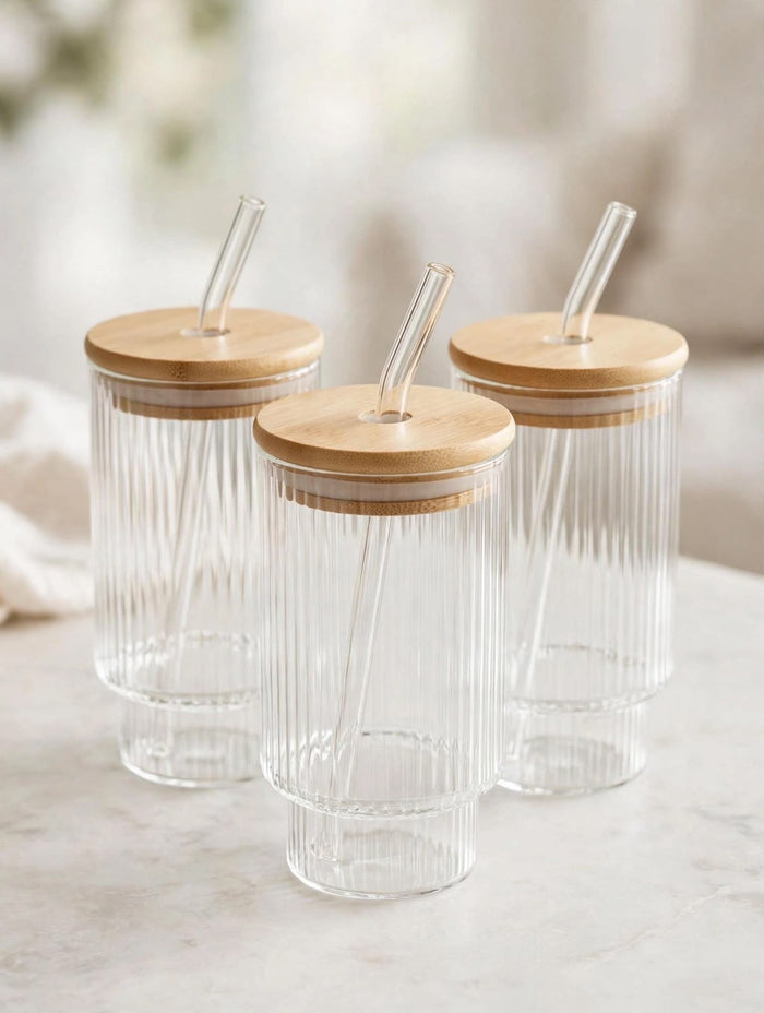 Trendiest ribbed glass tumbler set with bamboo lids and reusable glass straws on a marble surface