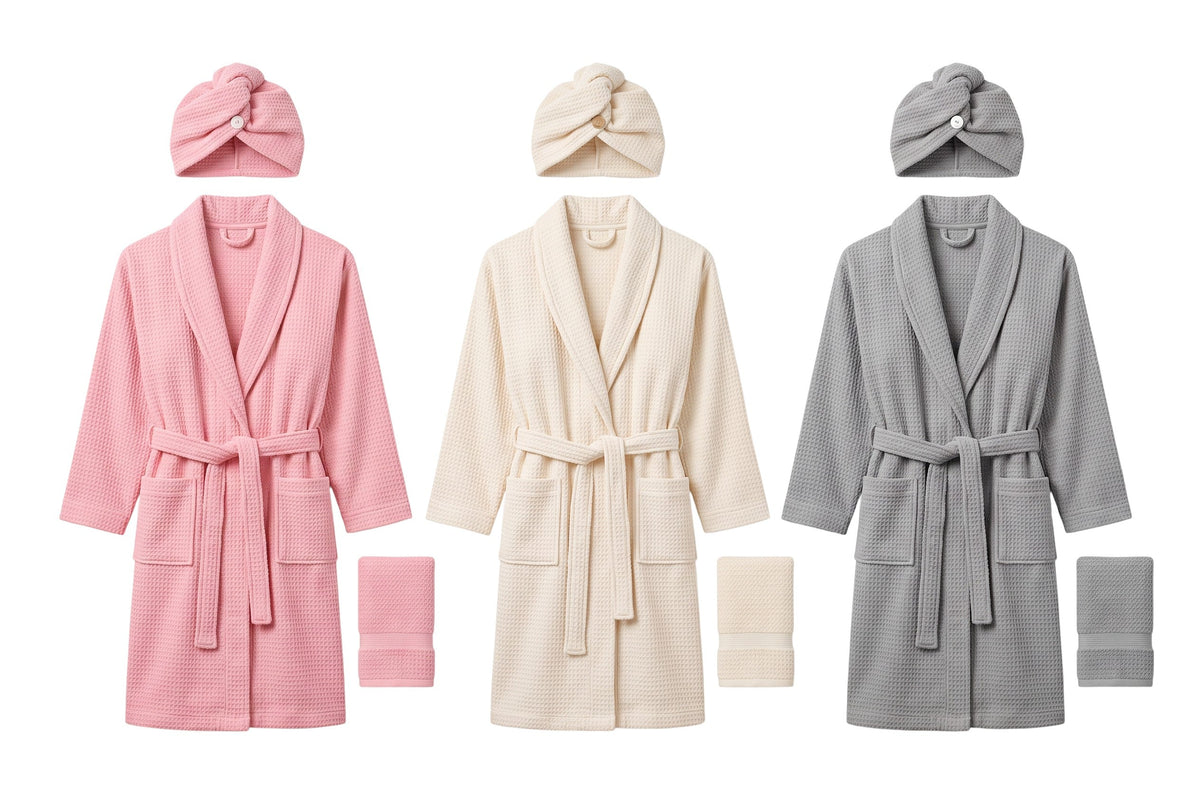 Trendiest spa bathrobe set in pink, cream, and grey with matching shower caps and face towels in waffle-weave fabric.