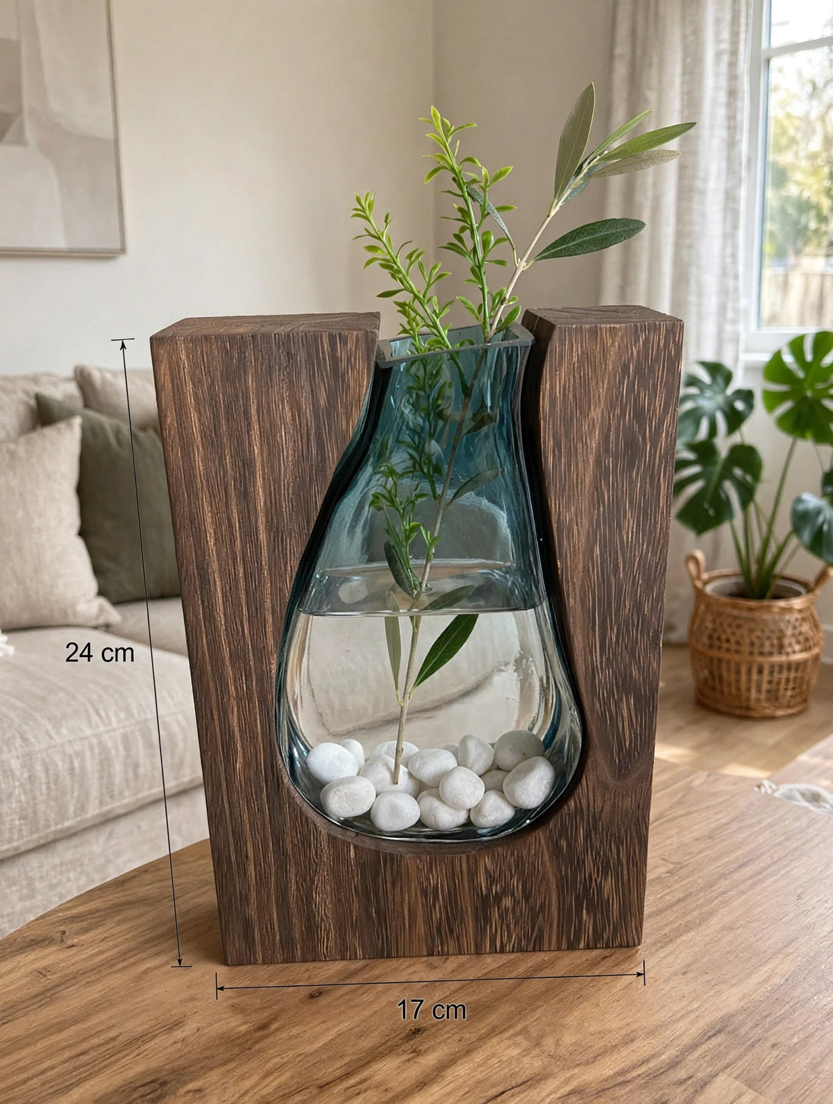 Trendiest handcrafted dark wood vase with a blue glass insert holding an olive branch and white decorative stones.